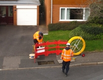 Men at a BT hole feeding in yellow cable